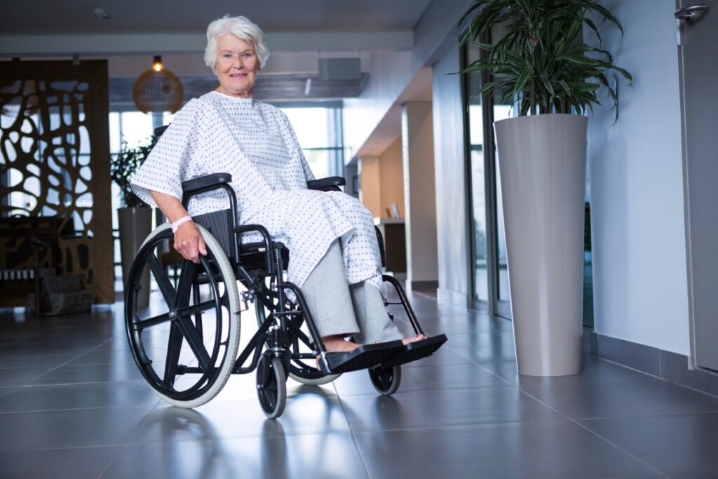 Disabled senior patient on wheelchair in hospital corridor